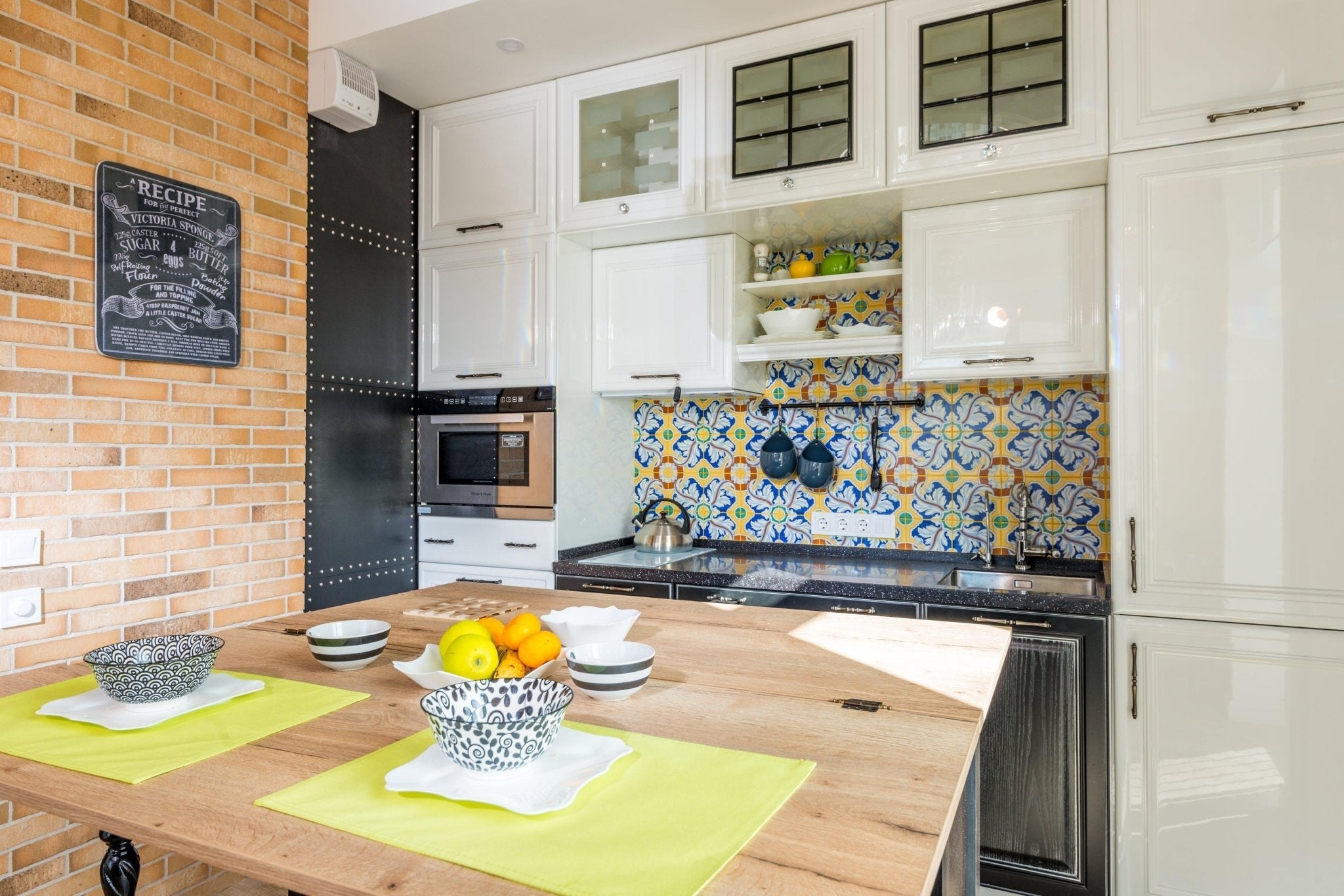The Yellow Oranges In The Fruit Dishes,Tea Tray On The Yellow Rugs,The Dining Room white Cabinet With Yellow Wall Painting,All show The Creativity of The Designer,Wooden Table With 4-Stainess Metal Legs Connect Them All.