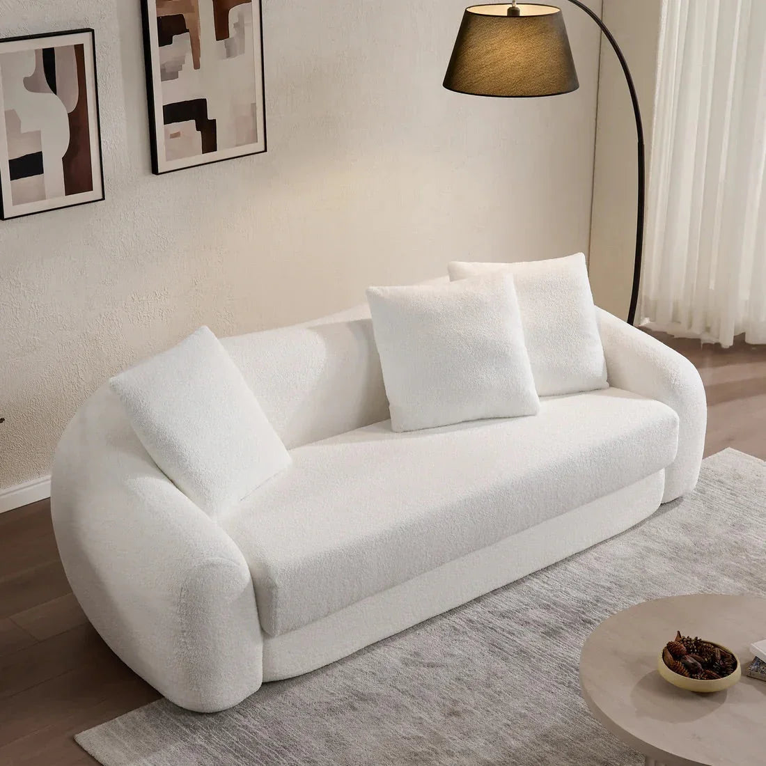 Modern living room with white boucle Nimbus sofa, abstract wall art, floor lamp, and rug