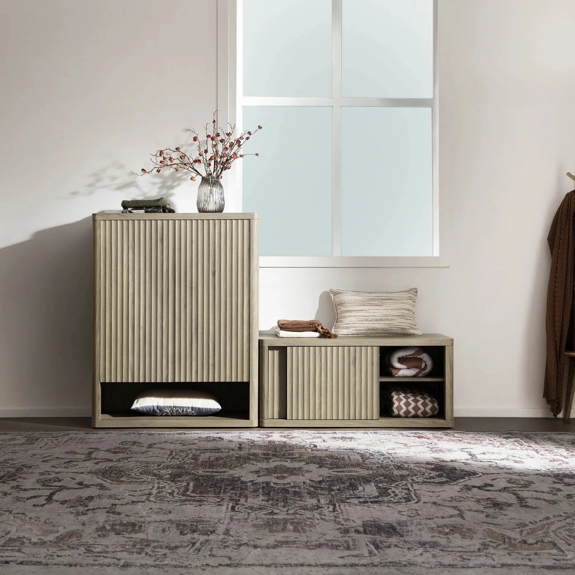Modern living room with functional storage furniture, decorative vase, and cozy pillows