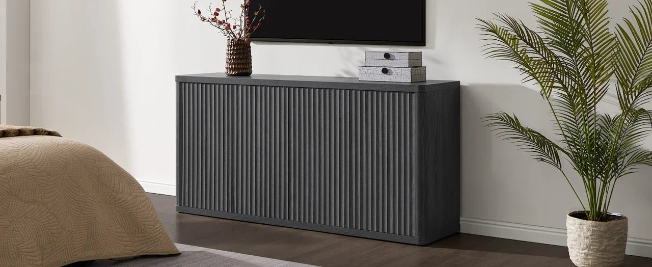 Modern dark wood sideboard with ribbed doors in bedroom, decor and potted plant nearby