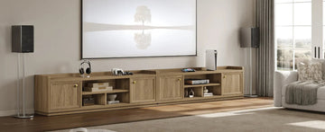 Modern living room with wooden TV console, large artwork, speakers, and gaming devices