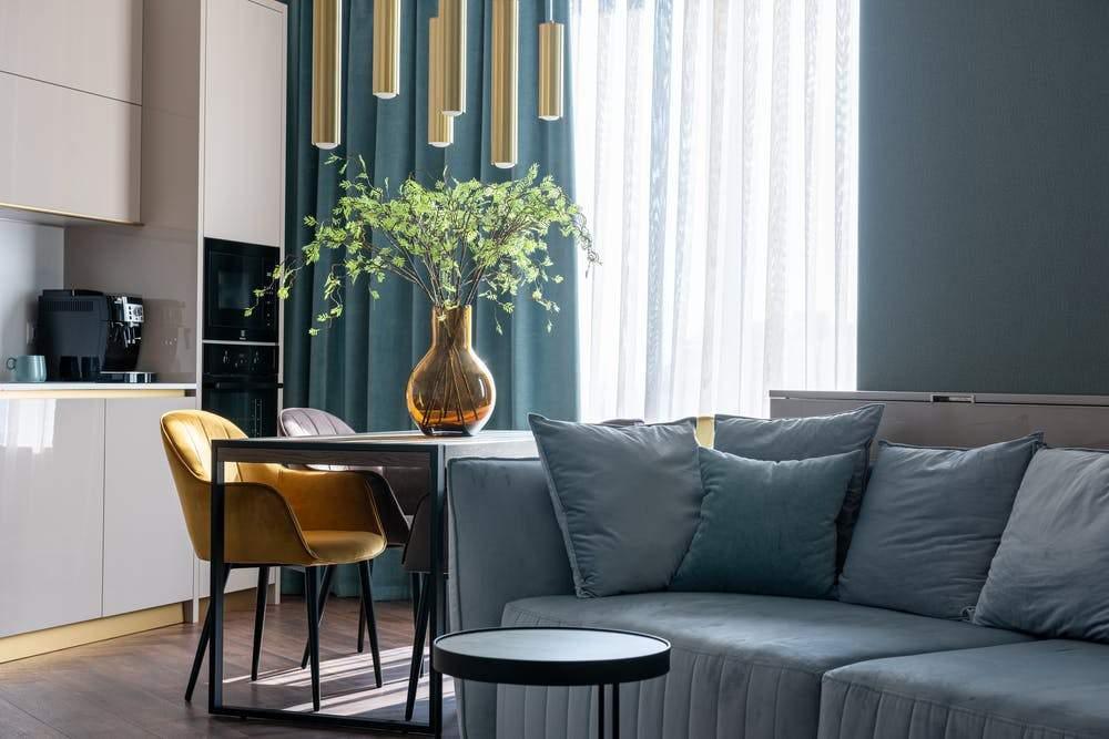 Modern small dining table with yellow chairs, gold pendant lights and a vase in a cozy kitchen