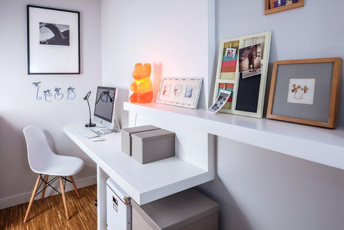 Modern home office desk with computer, white chair, orange bear lamp and decor accents