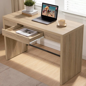 Modern oak office desk with drawer, laptop, plant, books, and coffee cup in a bright room