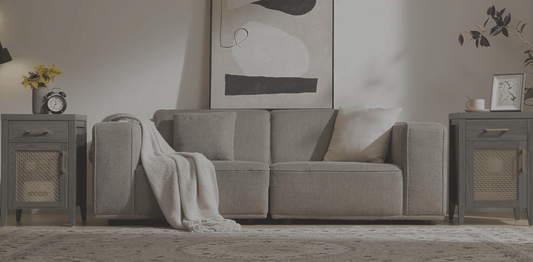 Modern living room with gray sofa, abstract wall art, decorative pillows, textured rug, and two dark wood side tables