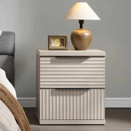Modern light wood nightstand with ribbed drawers, table lamp, and photo frame in a bedroom