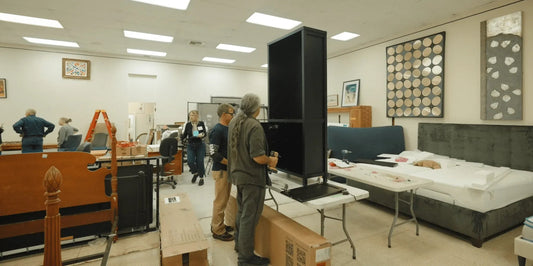 Volunteers assembling donated furniture in a brightly lit California relief center