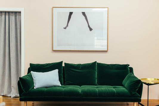 Green velvet sofa with light pillow in modern living room, gold side table, framed art above