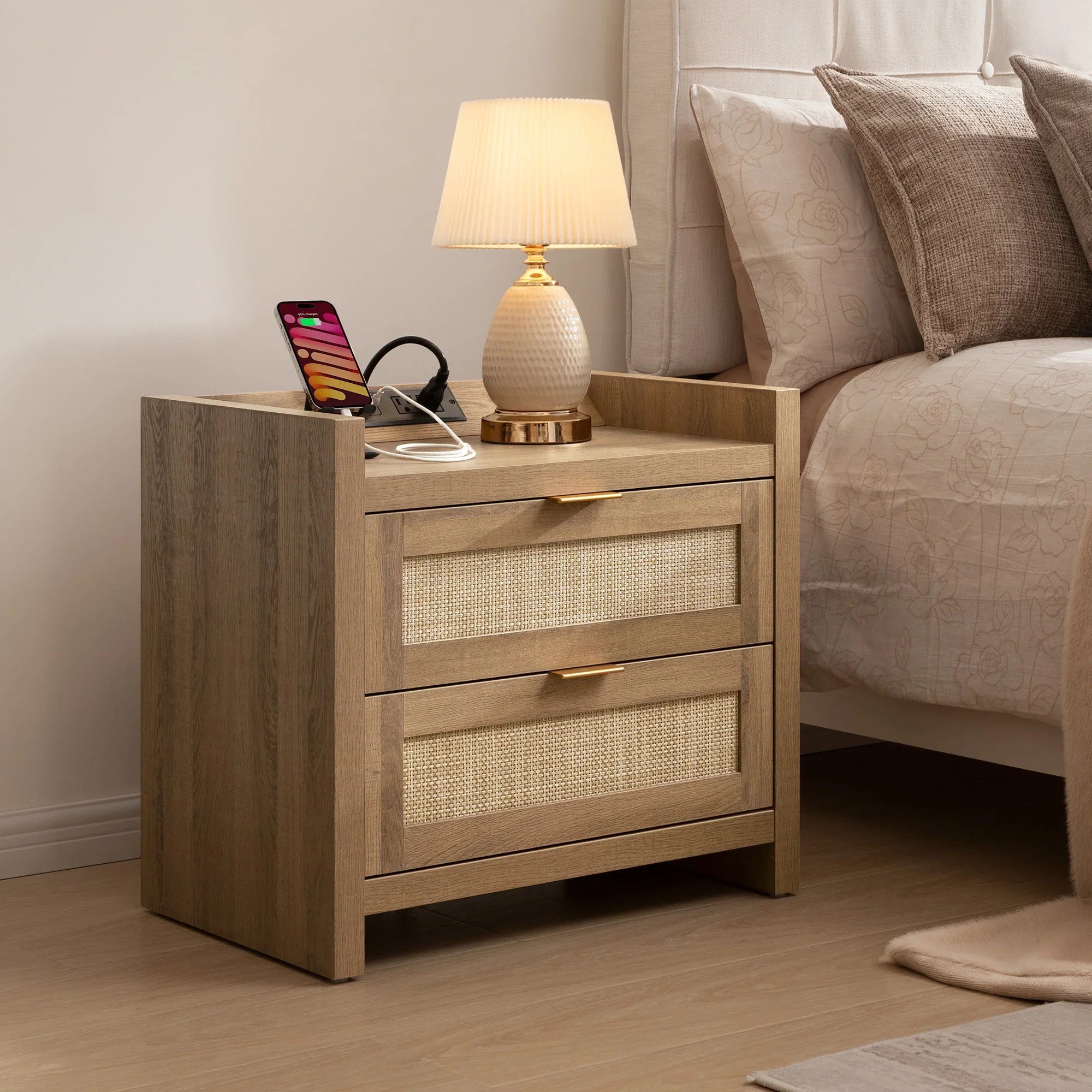 Wooden nightstand with lamp, phone, and charging station beside beige bed in modern bedroom
