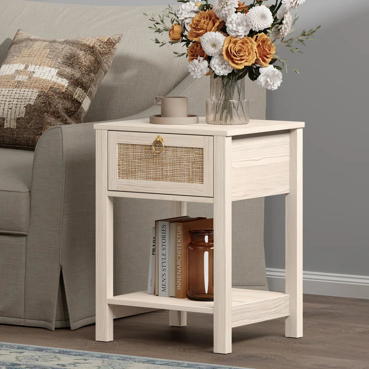 Light wood nightstand with rattan drawer, floral vase, coffee cup, books, and amber jar