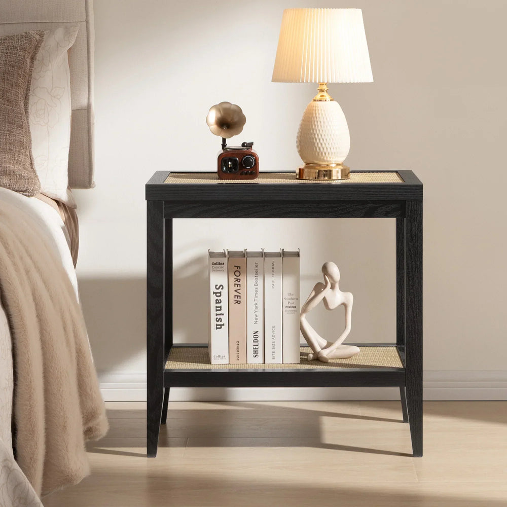 Modern black nightstand with books, abstract sculpture, table lamp, and retro radio by bed