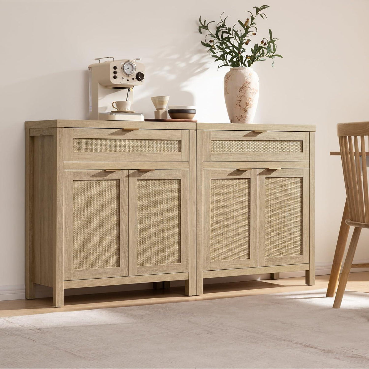 Light wood sideboard with woven cane doors, coffee maker, cups, and vase with branches