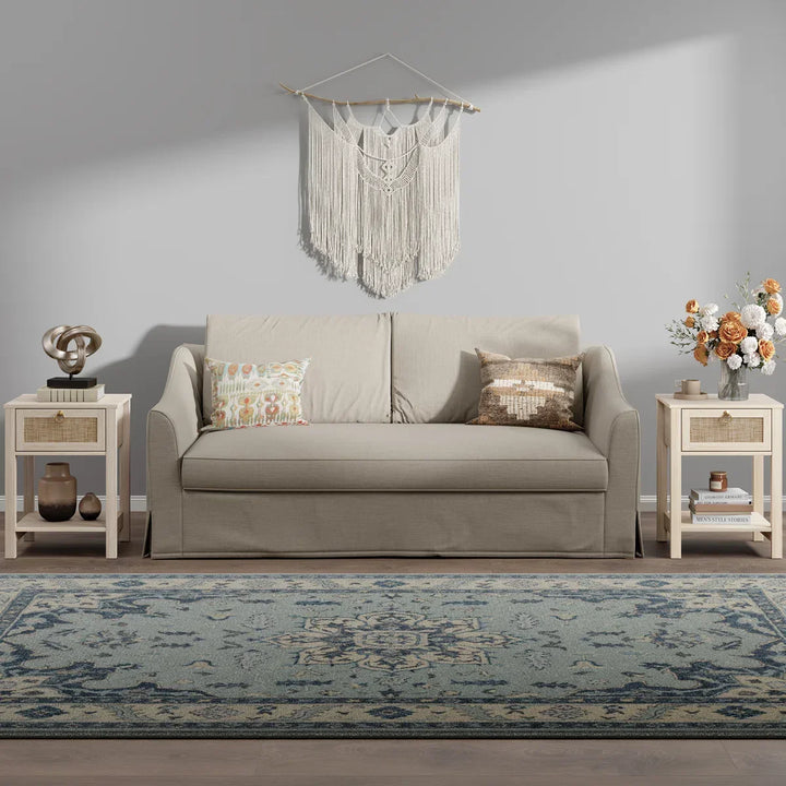 Beige sofa with decorative pillows, boho wall art, blue patterned rug, and side tables in modern living room