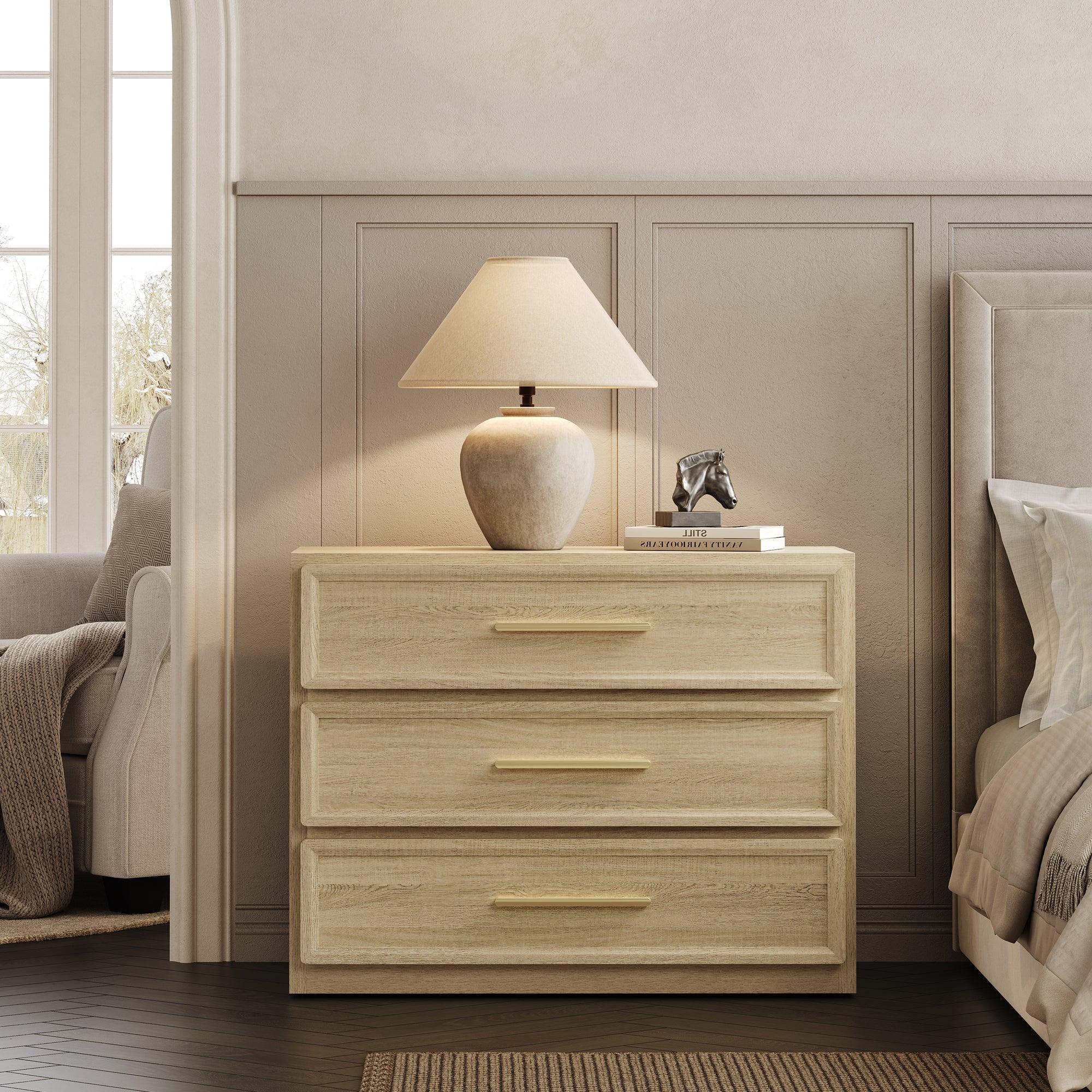 Light wood dresser with three drawers, table lamp, books, and horse sculpture in bedroom