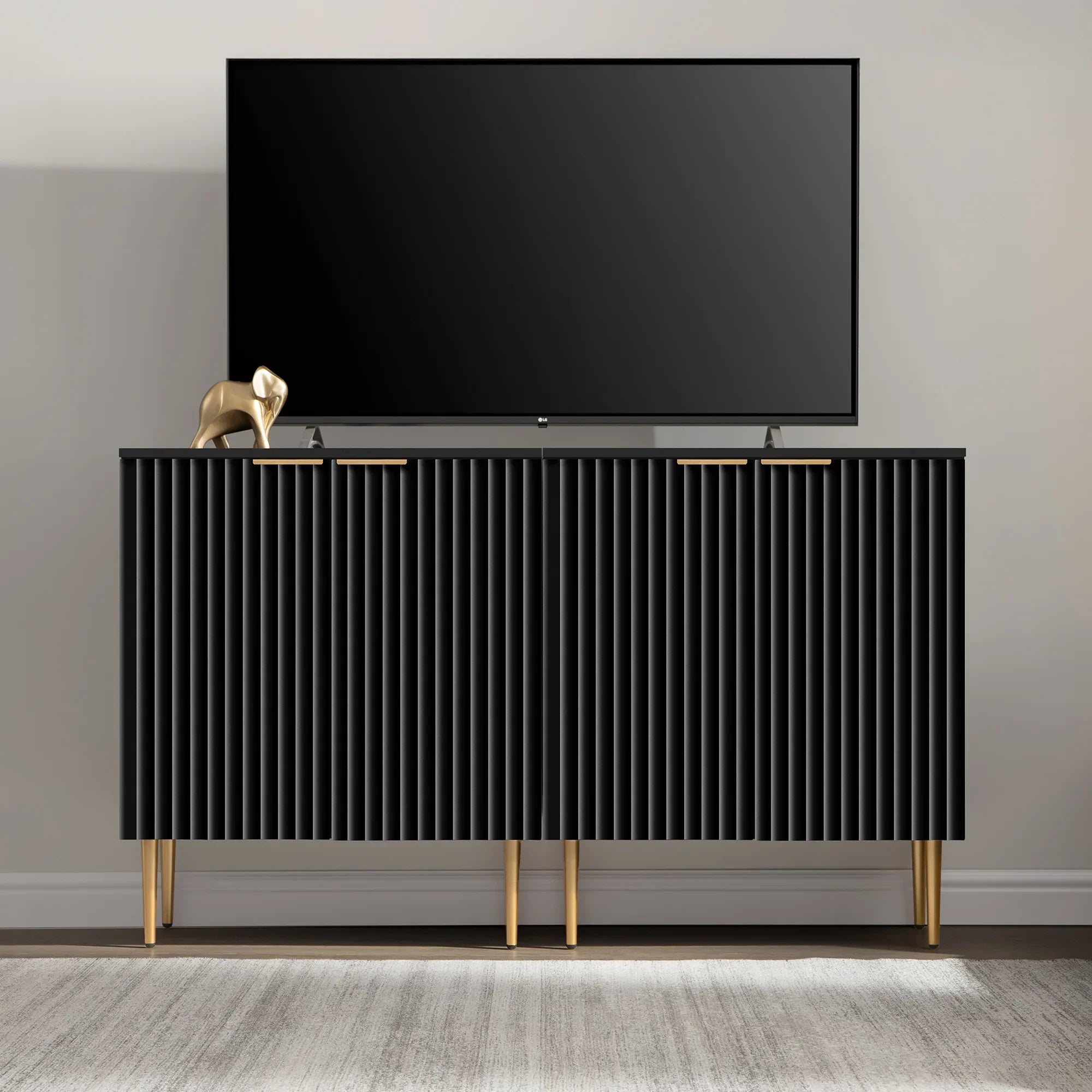 Modern black TV stand with gold legs and decor elephant, flat screen TV on top