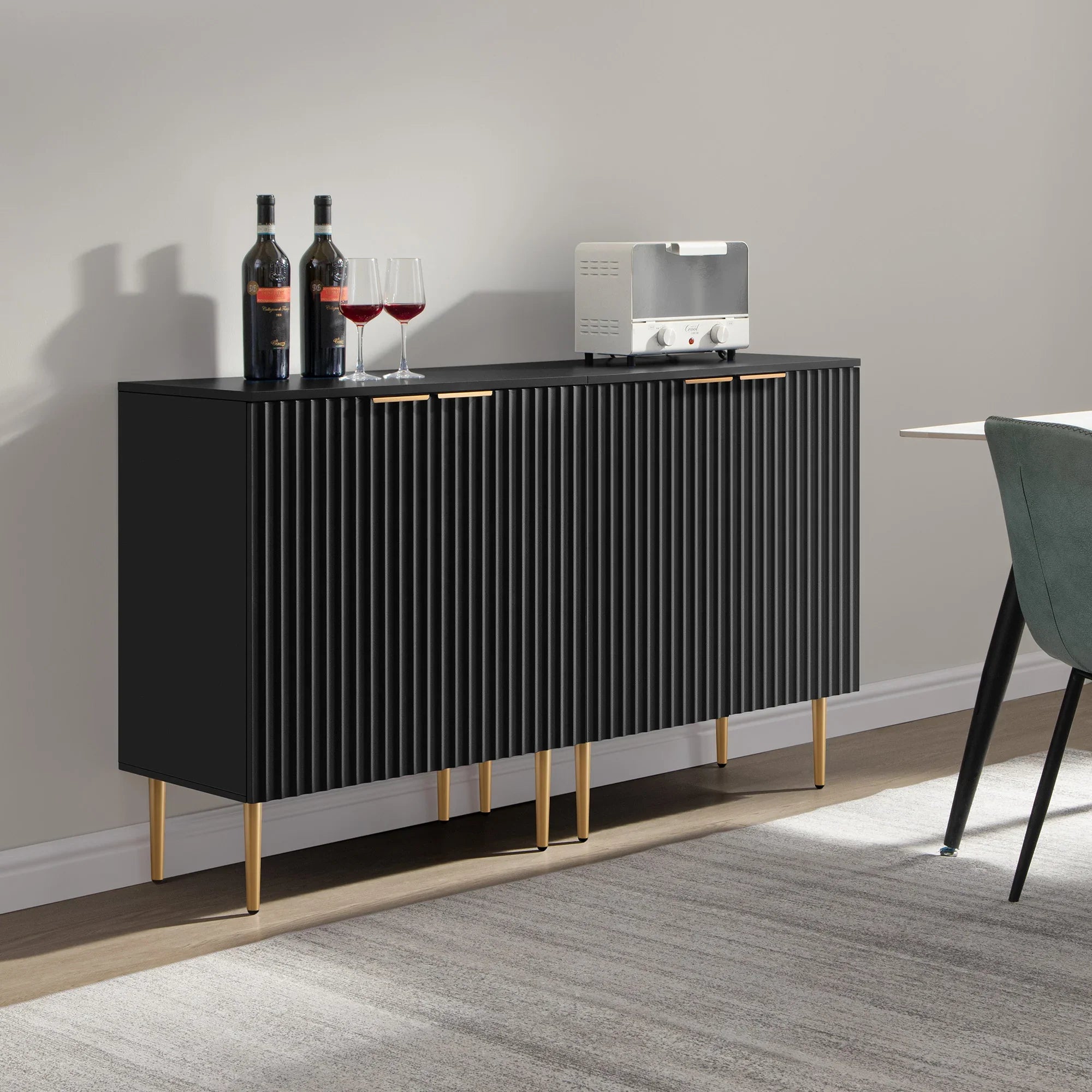 Modern black sideboard with gold legs, wine bottles, glasses, and a toaster in a dining room