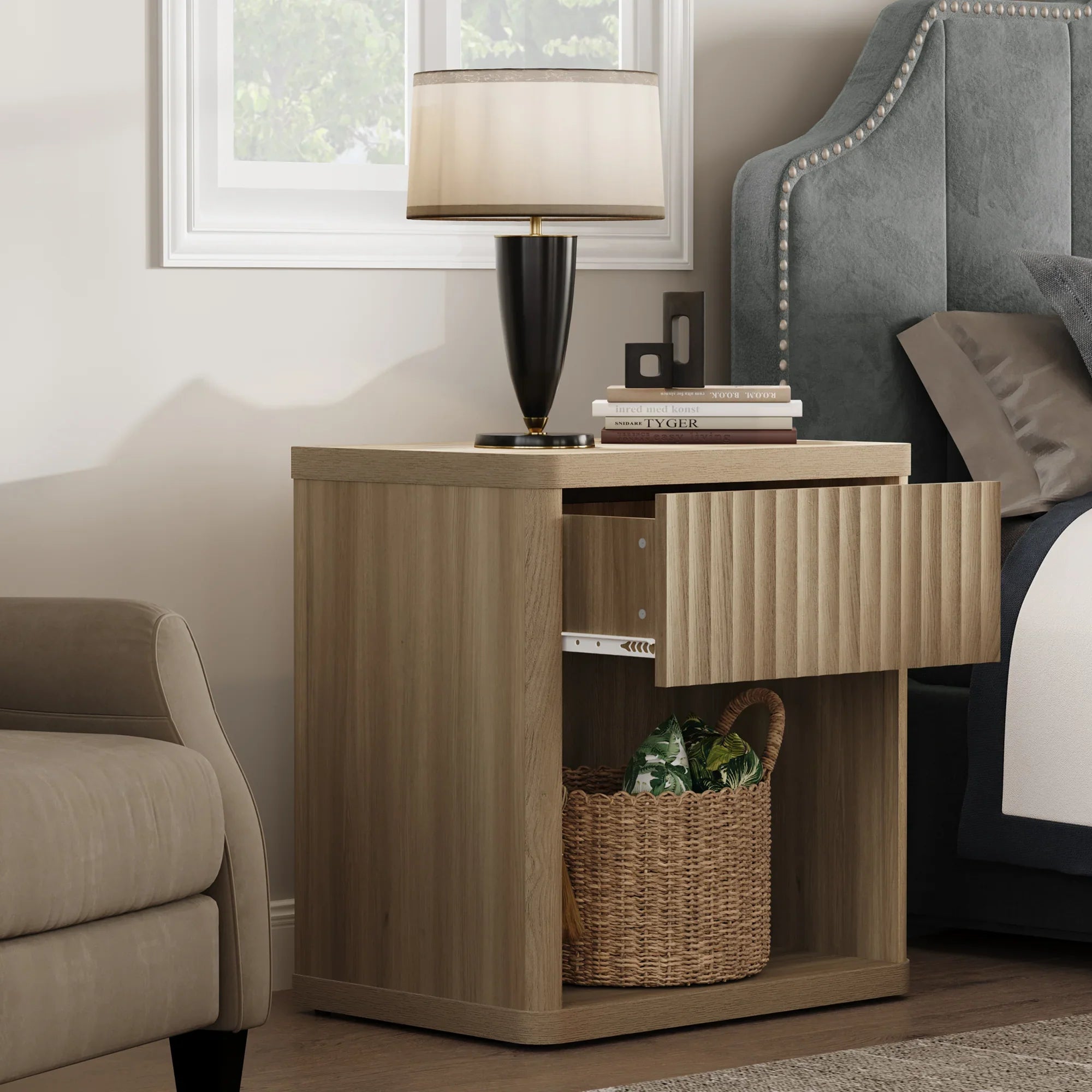 Modern oak nightstand with open drawer, lamp, books, and a woven basket in a bedroom