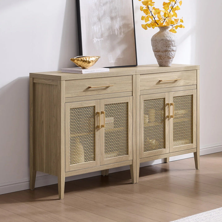 Modern light wood sideboard with cane doors, gold handles, vase, and artwork in bright room.