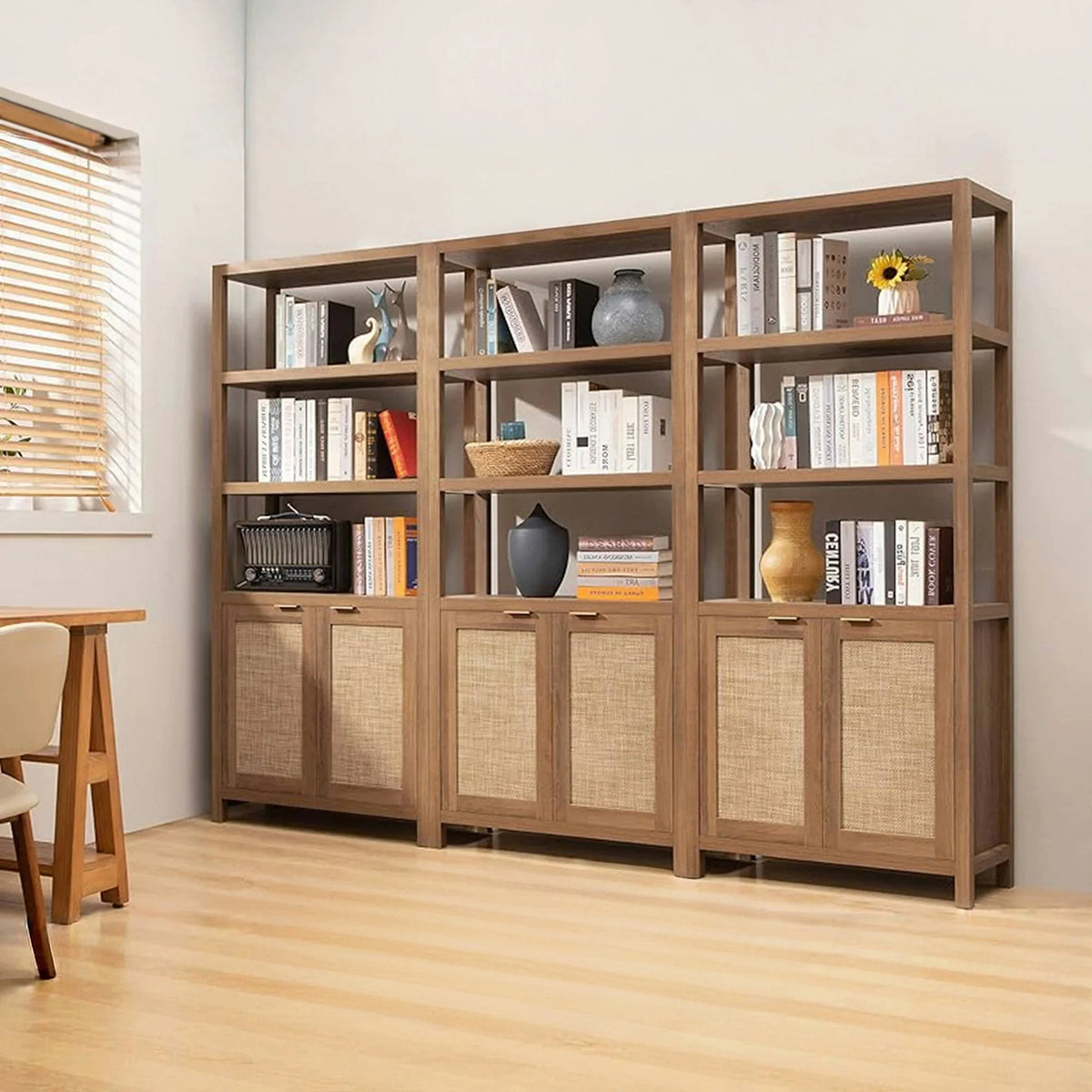 Modern wood bookcase with open shelves, rattan cabinet doors, books, vases, and decor in bright room