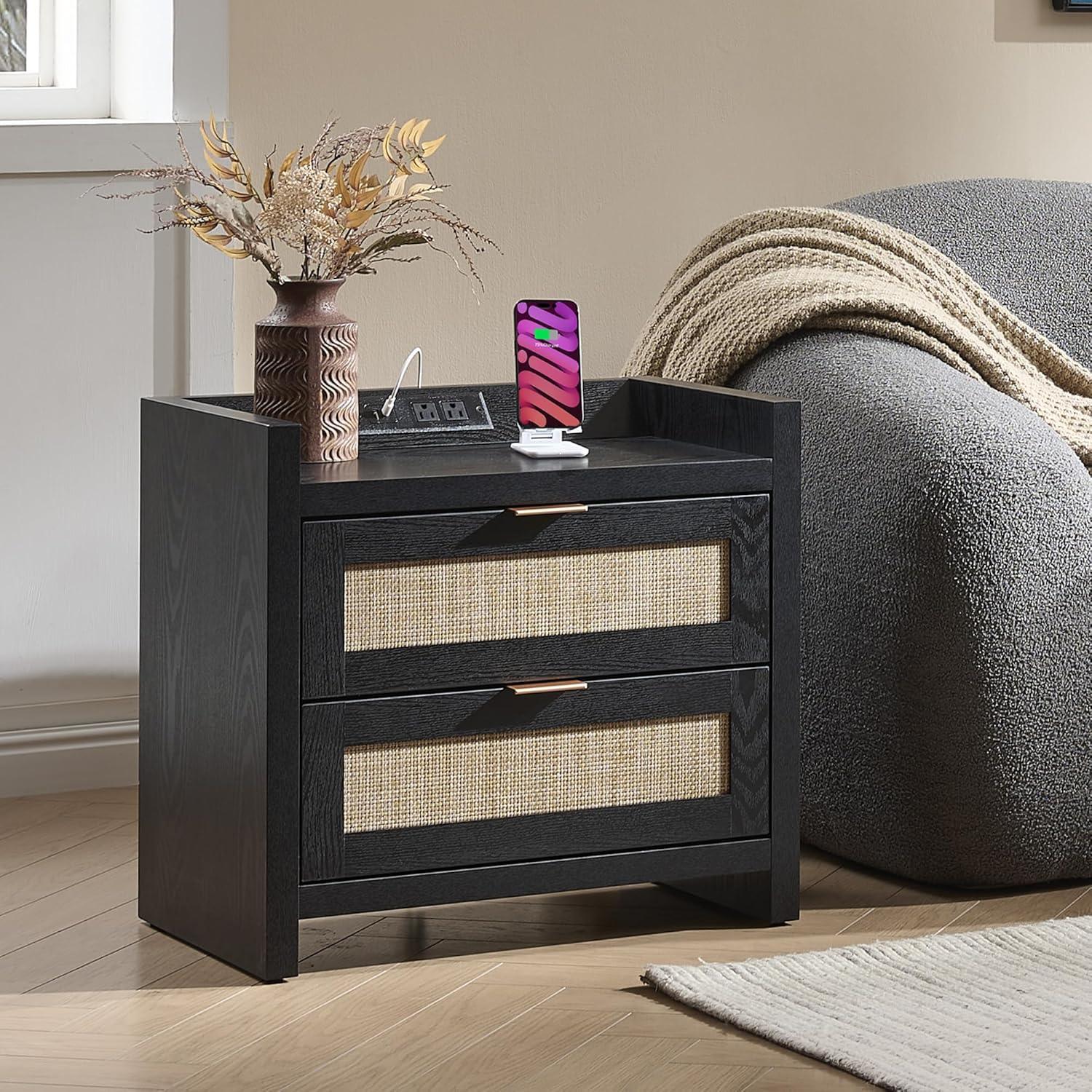 Modern black nightstand with rattan drawers, vase, charging phone, and cozy armchair