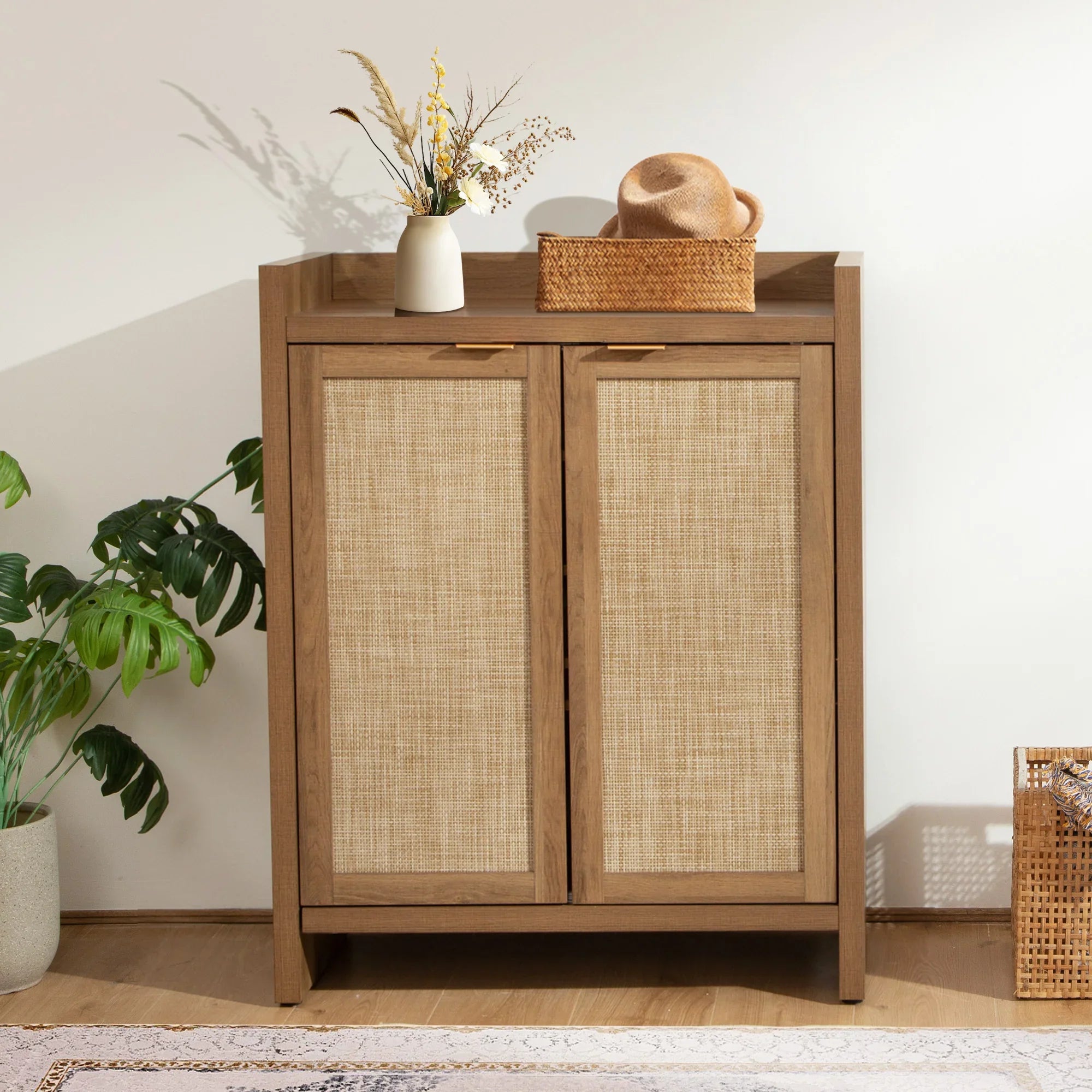 Modern wooden cabinet with woven doors, rattan basket, and vase with dried flowers