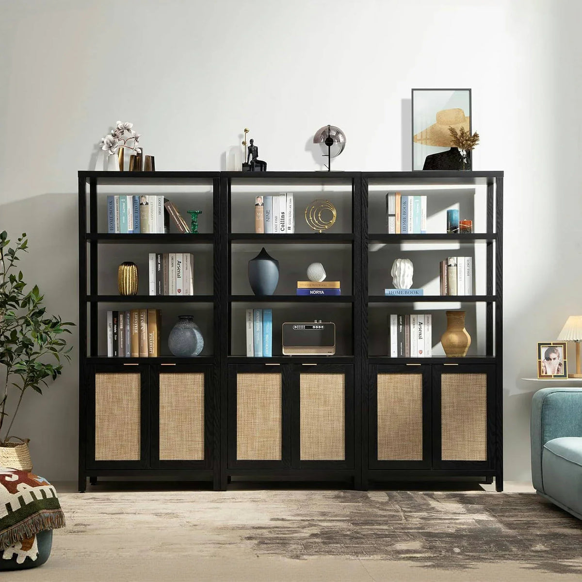 Modern black bookshelf with books, decorative vases, art, and wicker cabinet doors in living room