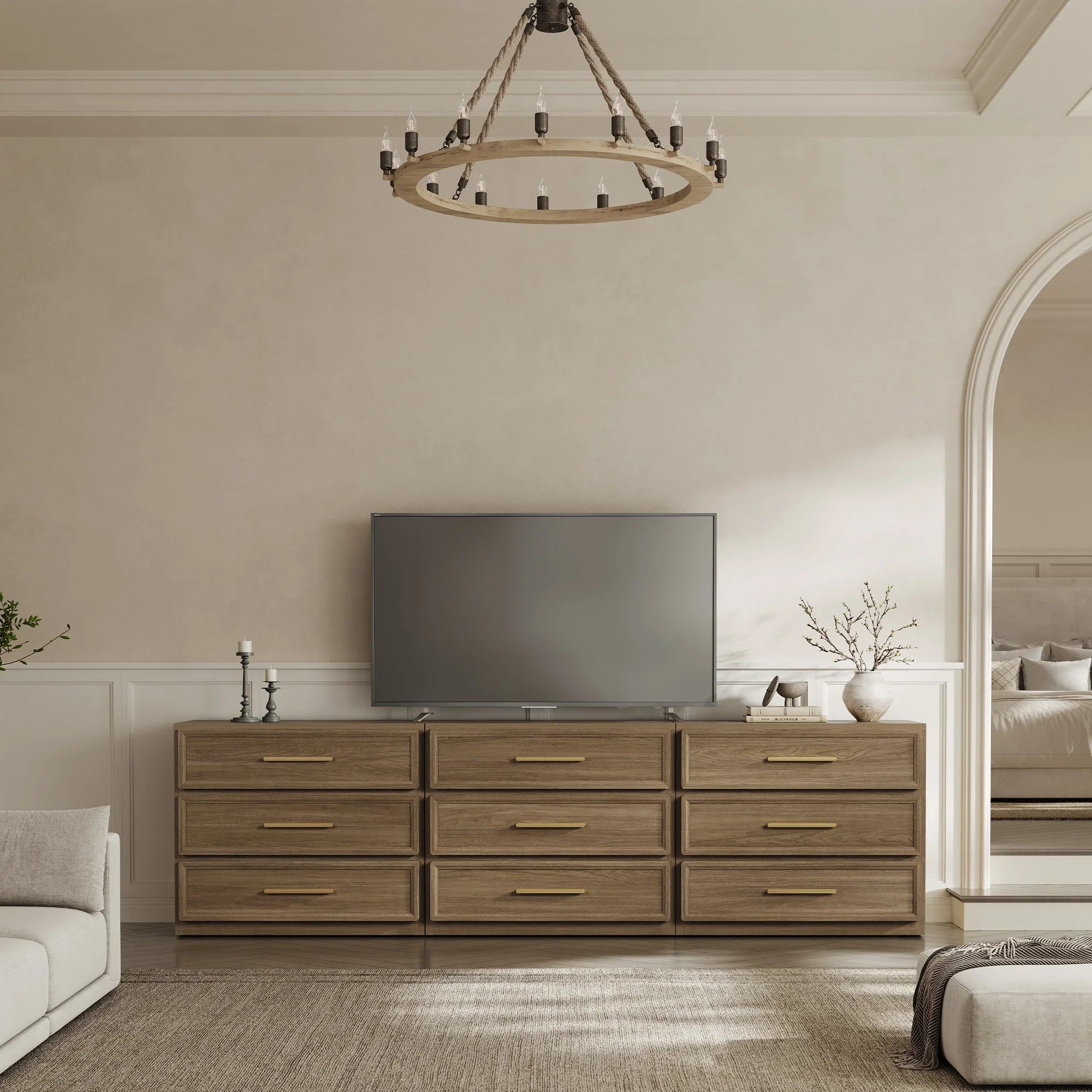 Modern living room with flat-screen TV on wooden dresser, beige walls, and chandelier lighting