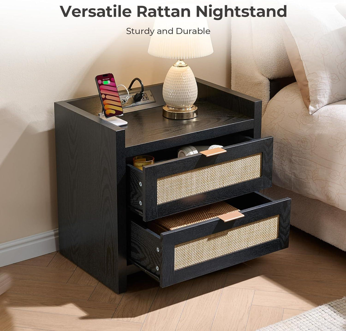 Black rattan nightstand with drawers, phone, lamp, and storage beside bed